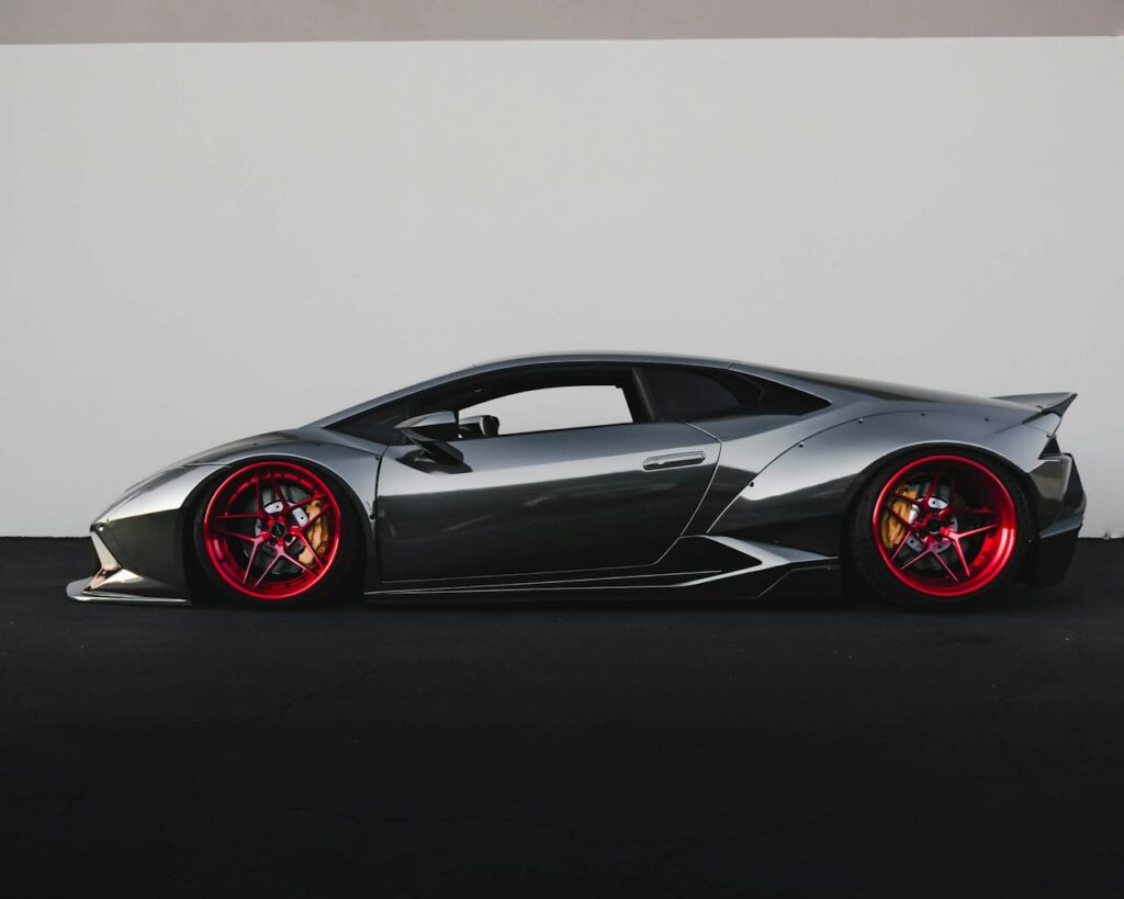 Grey Lamborghini sports car with distinctive red rims parked outdoors.