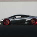 Grey Lamborghini sports car with distinctive red rims parked outdoors.